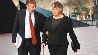 美国加州圣迭戈市前市长欧康纳（右）于14日出庭应讯后，手持拐杖，在律师搀扶下走出法院。